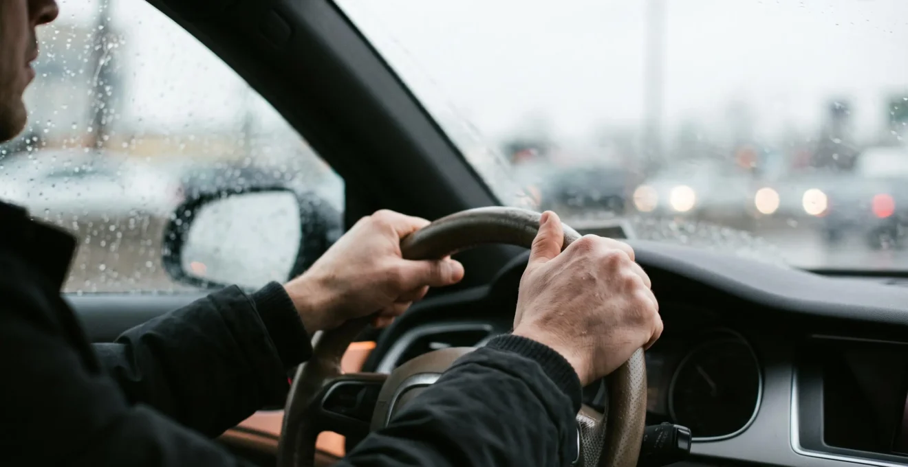 Gros plan sur les mains d'un conducteur concentre tenant fermement le volant pendant une conduite sous une pluie battante