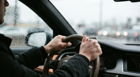 Gros plan sur les mains d'un conducteur concentre tenant fermement le volant pendant une conduite sous une pluie battante
